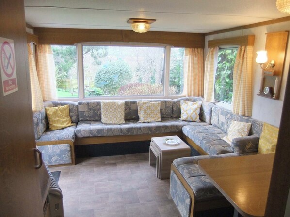 A cozy living area with a sofa set, a small table, and a window with curtains. - Harmony Country Lodge (Burniston)
