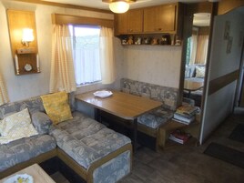 Una kitchenette compacta con una mesa de madera, un banco empotrado y un estante pequeño con adornos.