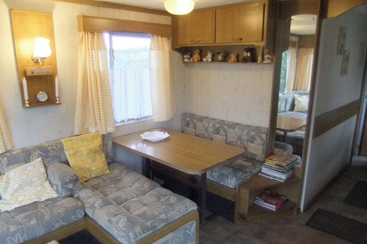 A compact RV interior with a sofa, a small dining table, and a kitchenette area.