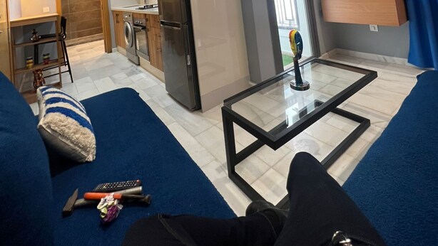 Un salon moderne avec un canapé, une table basse et un coin cuisine à l’arrière-plan.