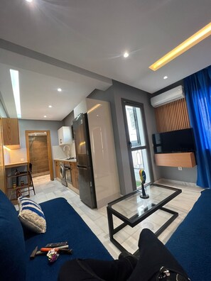 Een moderne woonkamer met een bank, salontafel en een keuken op de achtergrond.