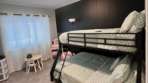 A bunk bed room with a desk and chair, a lamp, and a window with curtains. - Historic Deereville Home Pet Friendly! (Dubuque)