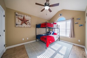 A bedroom with a bunk bed, a ceiling fan, a star decoration, and a window with curtains. - Candy Land Lane- 3 Bedrooms | Retro Game Room! (Abilene)