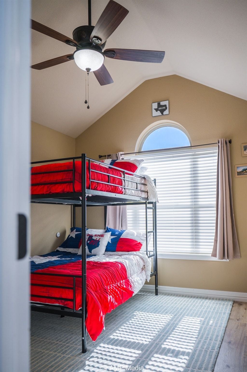 A room with bunk beds, a ceiling fan, a window with blinds, and a rug.