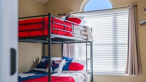 A room with bunk beds, a ceiling fan, a window with blinds, and a rug. - Candy Land Lane- 3 Bedrooms | Retro Game Room! (Abilene)