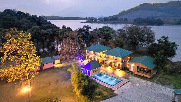 A large house with a swimming pool, surrounded by trees and a lake. - Ibex Resorts Malampuzha Kava Eco Camp (Malampuzha-I)