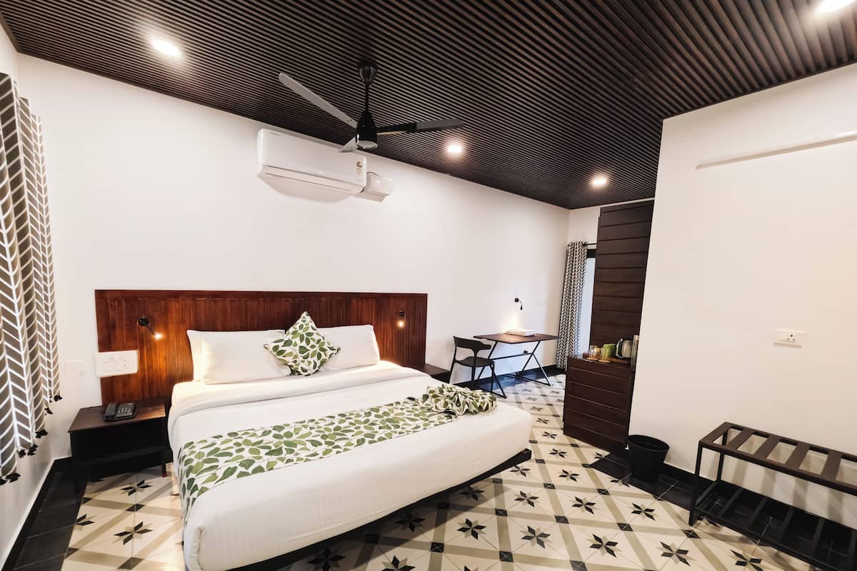 Una habitación de hotel moderna con una cama grande, un escritorio y un ventilador de techo.