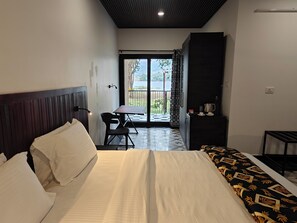 A hotel room with a bed, a desk, and a view of the outdoors. - Ibex Resorts Malampuzha Kava Eco Camp (Malampuzha-I)