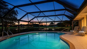 A swimming pool with a covered area, surrounded by a patio with chairs. - Greenside in Palm Beach Gardens - Private Pool & Golf Course Views! (Palm Beach Gardens)
