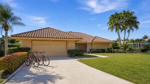 A residential house with a tiled roof, a garage, and a well-maintained lawn. - Greenside in Palm Beach Gardens - Private Pool & Golf Course Views! (Palm Beach Gardens)