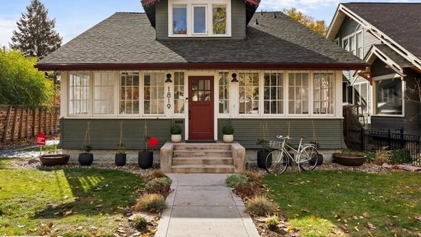 A two-story house with a red door, white trim, and a covered front porch. There are potted plants and a bicycle parked outside. - Spacious downtown loft, with soaking tub&gym access-walk to BSU and Boise River! (Boise)