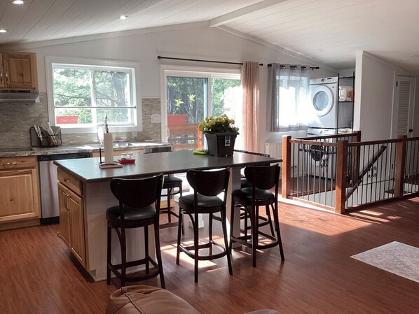 A modern kitchen with a central island, bar stools, and a view of the outdoors.