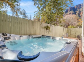Un jacuzzi con cerca de madera y árboles al fondo.
