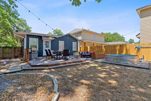 Un patio trasero con una terraza, mobiliario exterior y un jacuzzi.