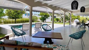 Un área de patio al aire libre con piscina, sillas de descanso y una mesa de comedor.
