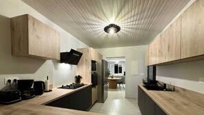 Una cocina moderna con armarios de madera, una isla central y un comedor al fondo.