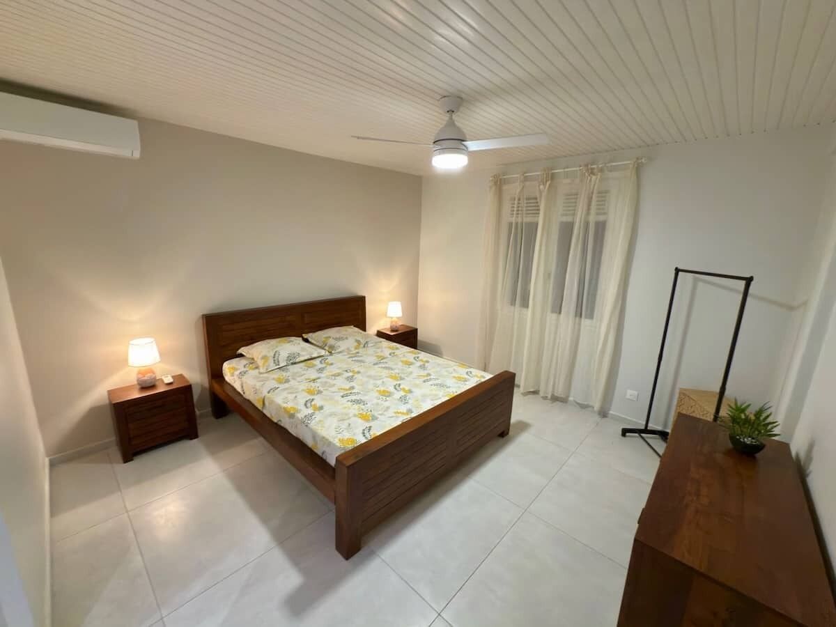 Une chambre à coucher comprenant un lit, des tables de chevet, un ventilateur de plafond et un lampadaire.