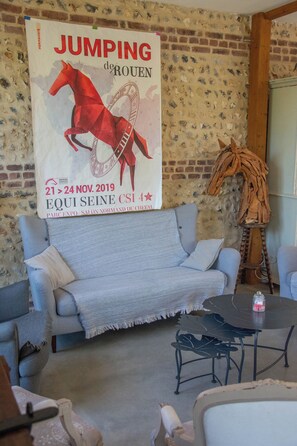 A room with a blue sofa, a small round table, and a poster on the wall. - Armand's barn (Mentheville)