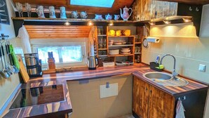 Eine kleine Küche mit Holzausstattung, einem Spülbecken und verschiedenen Küchenutensilien.