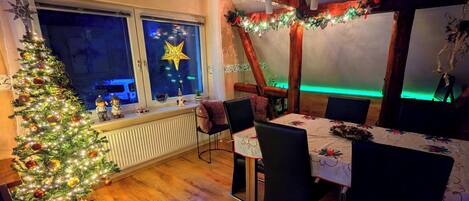 Una zona de menjador acollidora amb un arbre de Nadal, una estrella decorativa a la finestra i un sostre de fusta.