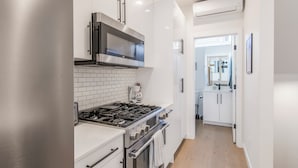 Una cocina moderna con armarios blancos, electrodomésticos de acero inoxidable y un salpicadero de azulejos.