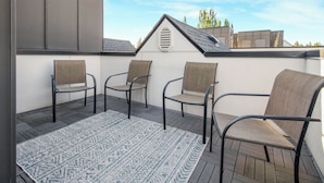 Una terraza en la azotea con tres sillas y un tapete estampado.