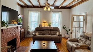 A living room with a fireplace, a sofa, a coffee table, and a television. - Beautiful Civil War home in Downtown Gettysburg! (Gettysburg)