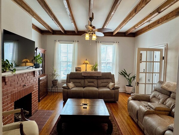 Una sala de estar con chimenea, un sofá, una mesa de centro y un televisor.