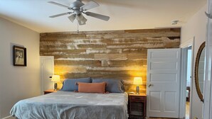 A bedroom with a wooden headboard, a bed with pillows, two bedside lamps, a ceiling fan, and a door with a mirror. - Beautiful Civil War home in Downtown Gettysburg! (Gettysburg)