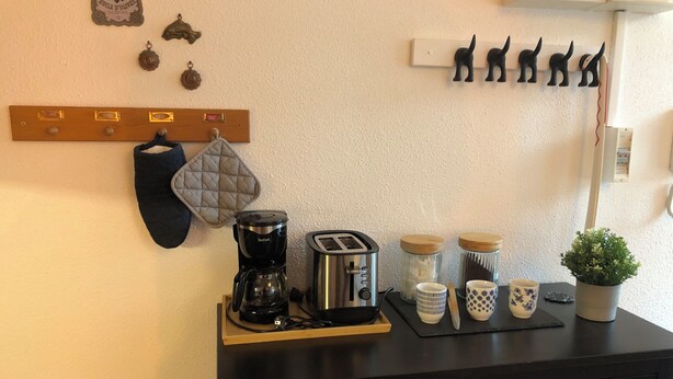 Uma bancada de cozinha com cafeteira, torradeira e potes sobre um balcão preto.