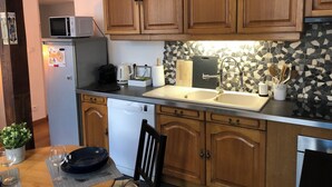 Cozinha com armários de madeira, micro-ondas, lava-louças, pia e painel de azulejos.