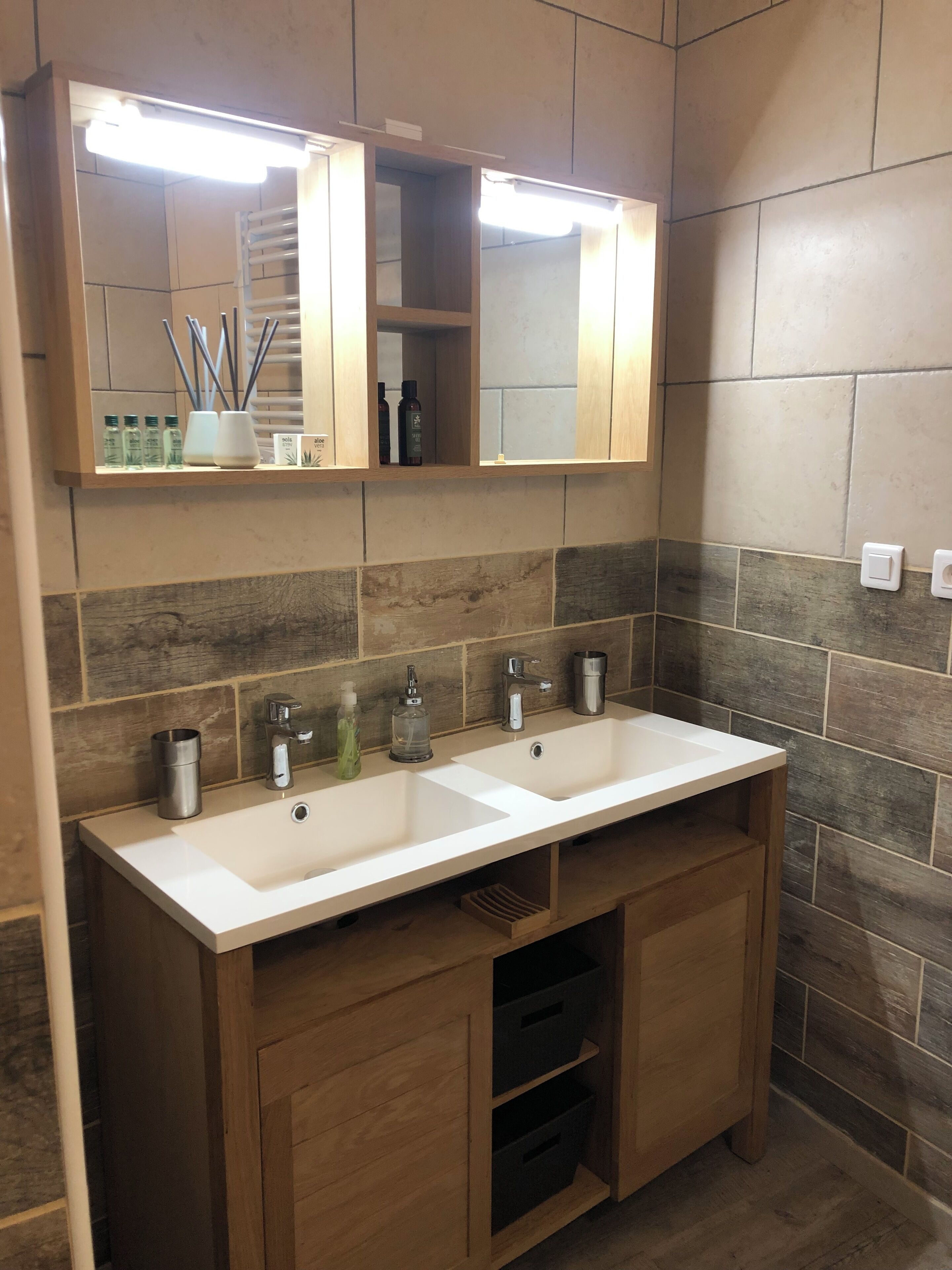 Un bagno con due lavandini, uno specchio e un mobiletto in legno con cassetti.