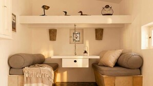 A cozy room with a built-in bench seating area, a small shelf with decorative items, and a hanging light fixture. - Can Joseph II Can Toni Platera (Formentera)