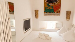 A bedroom with a bed, a TV, and artwork on the wall. - Can Joseph II Can Toni Platera (Formentera)