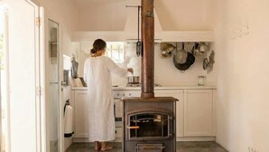 A kitchen with a wood-burning stove, white cabinets, and a glass door leading to another room. - Can Joseph II Can Toni Platera (Formentera)