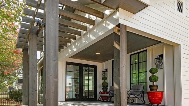 A covered patio with steps leading to a door, a seating area with chairs and a table, and a potted plant. - Luxury Walk-to-Stadium Stay with Backyard Retreat! (Tuscaloosa)