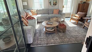 A spacious living room with a large sectional sofa, a round coffee table, and a fireplace. - Luxury Walk-to-Stadium Stay with Backyard Retreat! (Tuscaloosa)