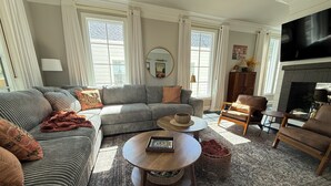 A cozy living room with a sectional sofa, a round coffee table, and a fireplace. - Luxury Walk-to-Stadium Stay with Backyard Retreat! (Tuscaloosa)