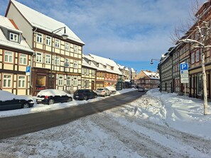A street lined with traditional half-timbered buildings, a parking sign, and snow-covered cars. - Vacation apartment Schöne Ecke (Wernigerode)