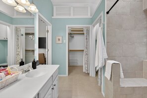 Een badkamer met een grote spiegel, twee wasbakken, een douche en een inloopkast.