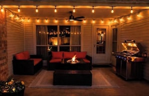 Eine Terrassensitzgruppe im Freien mit Feuerstelle, Sitzgelegenheiten und Grill.