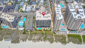 An aerial view of a coastal hotel with multiple buildings, a beach with umbrellas, and a pool area. - Perfect 1-bedroom ocean front condo in charming North Myrtle Beach sleeps 6 (North Myrtle Beach)
