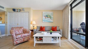 A living room with a sofa, a coffee table, a chair, and a painting on the wall. - Perfect 1-bedroom ocean front condo in charming North Myrtle Beach sleeps 6 (North Myrtle Beach)