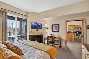 Una habitación de hotel con cama, chimenea, televisor, zona de comedor y cocina.