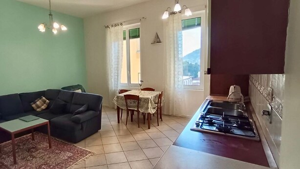 A living room with a sofa, coffee table, and dining area with chairs and a table. A kitchen with a stove is visible. - SANREMO IMPERATRICE CASINO' CITY CENTRE  threeroom flat for THE SANREMO FESTIVAL (Sanremo)