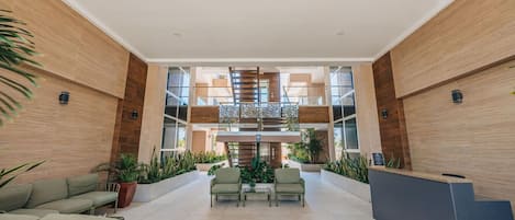 A spacious lobby with a central staircase, seating area, and reception desk.