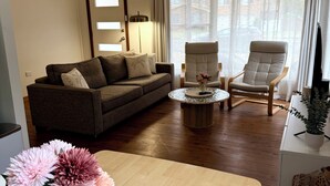 A living room with a sofa, two armchairs, a coffee table, and a TV stand. - Welcome to Saltwater Escape in Swansea. (Swansea)