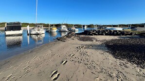 A marina with boats docked, a sandy beach, and a clear blue sky. - Welcome to Saltwater Escape in Swansea. (Swansea)