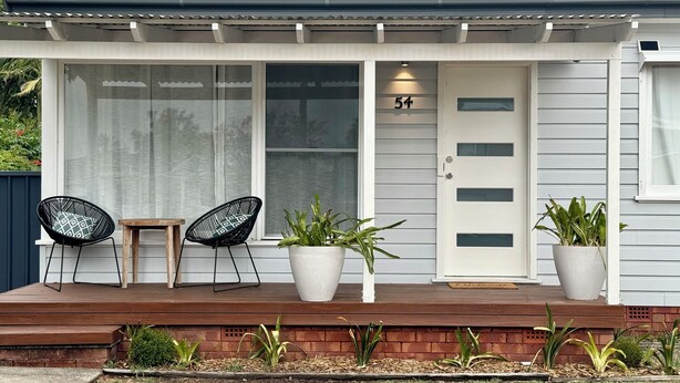 A house with a covered porch, two chairs, and potted plants. - Welcome to Saltwater Escape in Swansea. (Swansea)