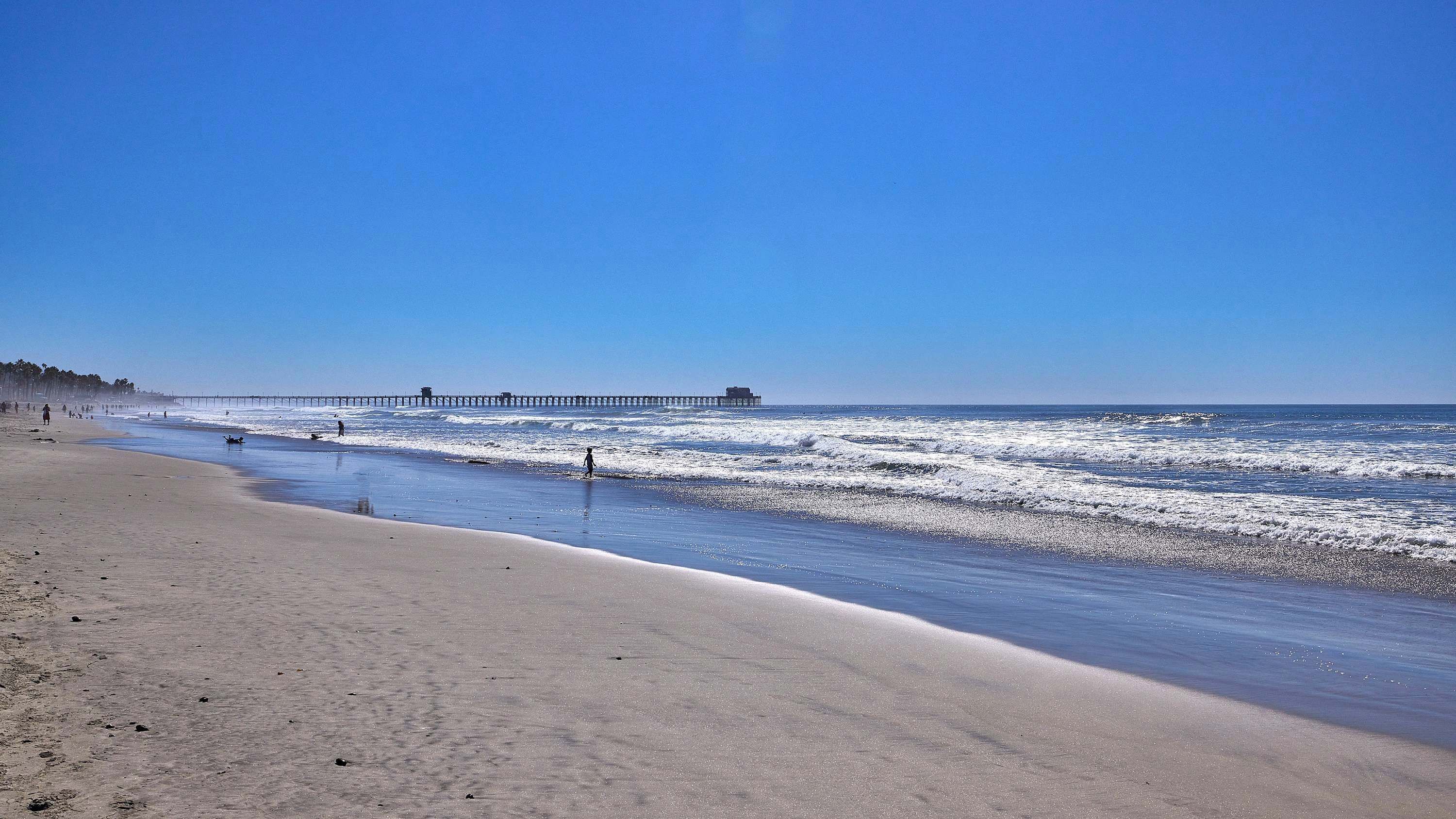 A beach with a pier extending into the ocean.